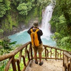 A hiker in front of a rainforest waterfall in Costa Rica